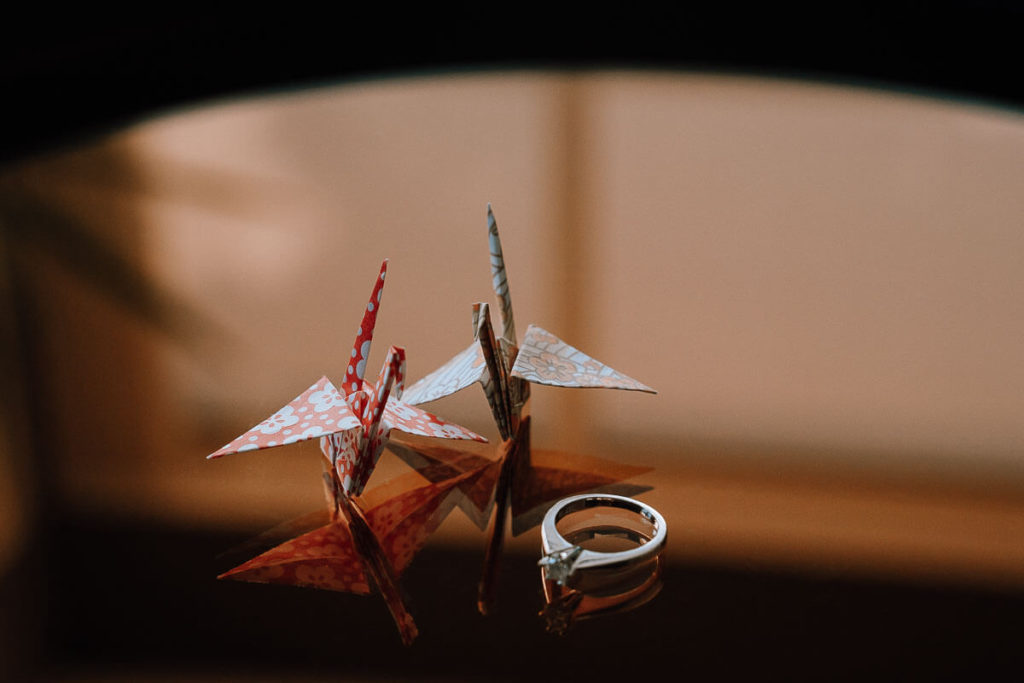 Close-up of folded paper Japanese birds with an engagement ring